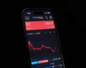 Smartphone screen showing StockRadars app with SET index at 1,454.47 in a red banner and a red price chart above a blue-trend area.